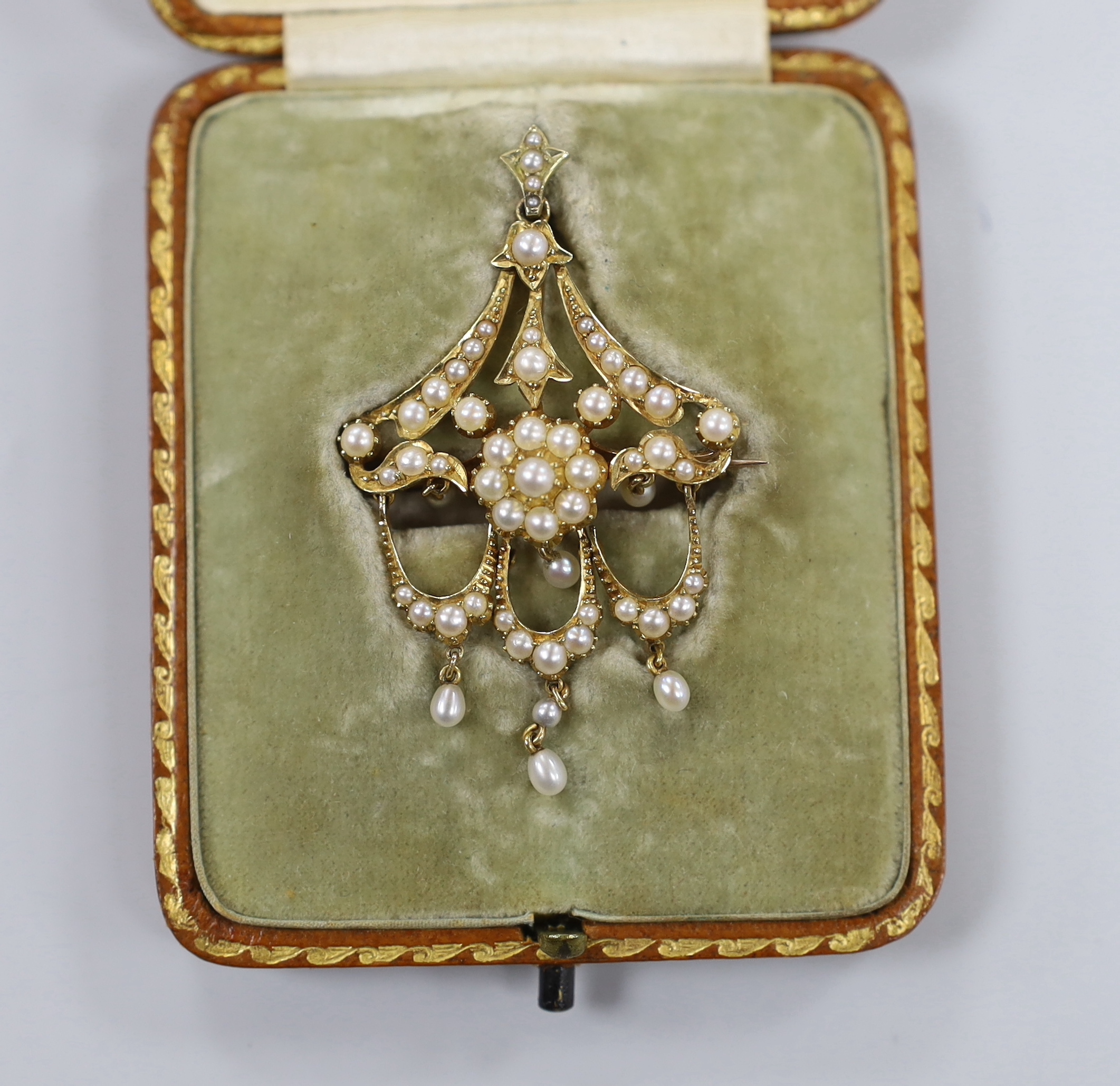 An Edwardian yellow metal and seed pearl set triple drop pendant brooch, 54mm, gross weight 7.5 grams, in original gilt tooled leather fitted case.